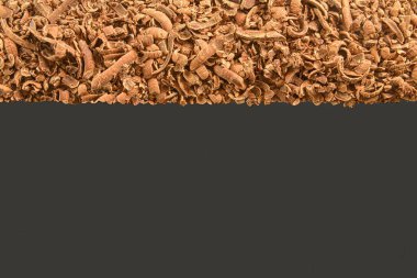 Scattered grated dark chocolate. Flat lay and large copy space. Chocolate shavings on a dark background.