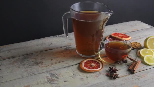 Horký čaj v džbánu a pohár s párou na dřevěném stole černém pozadí. Bílé venkovské pozadí. Zpomalený pohyb — Stock video