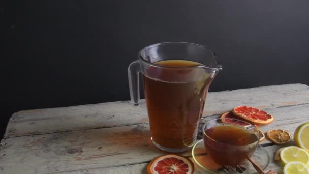Varmt te i en kanna och kopp med ånga på ett träbord svart bakgrund. Vit rustik bakgrund. Långsamma rörelser — Stockvideo