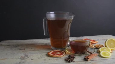 Cam çaydanlıkta sıcak çay ve ahşap masada buharlı bir fincan. Siyah arkaplan