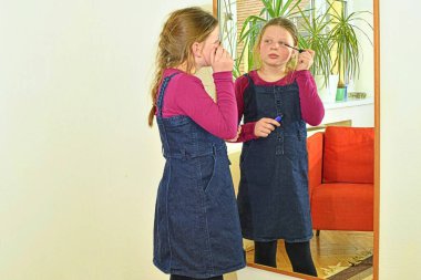 Makyaj yapan küçük bir kız. Anne ruju deneyen küçük bir kız, rimel - modern bir kadın olmayı öğreniyor.