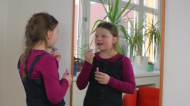 Evde makyajla oynayan sevimli küçük bir kız. Mutlu çocuk evde annesinin kozmetik ürünleriyle deney yapıyor. Kızın ayna yansıması.