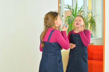 Makyaj yapan küçük bir kız. Anne ruju deneyen küçük bir kız, rimel - modern bir kadın olmayı öğreniyor..