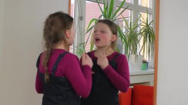 Evde makyajla oynayan sevimli küçük bir kız. Mutlu çocuk evde annesinin kozmetik ürünleriyle deney yapıyor. Kızın ayna yansıması..