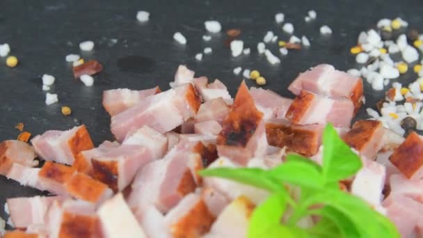 Bacon de dados, manjericão e temperos em bandeja de ardósia rotativa. Cubos de bacon fatiados, manjericão e temperos em uma placa de ardósia rotativa. Macro — Vídeo de Stock