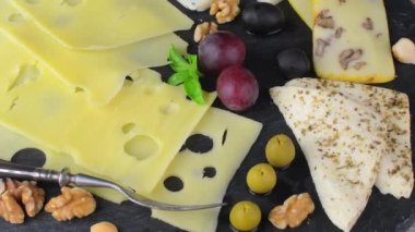 Peynir tabağı, çeşitli peynirler, üzümler, siyah arka planda fındıklar, kopyalama alanı. İtalyan peyniri ve meyve tabağı bal ve kayrak kaplama arka planda