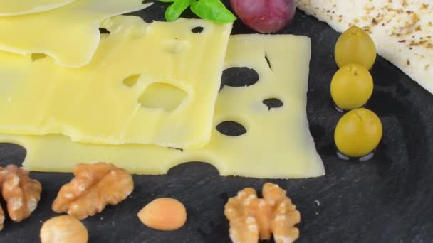 Sýrová placka. Emmental, sýr Camembert, sýr, chlebové tyčinky, vlašské ořechy, lískové ořechy, hrozny na otočném břidlicovém podnosu — Stock video