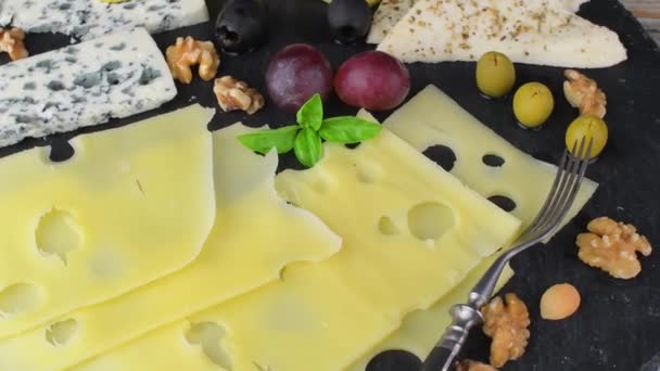 Piatto di formaggio con formaggi assortiti, uva, noci su fondo nero. Formaggio italiano e piatto di frutta. Ardesia sfondo rotante — Video Stock