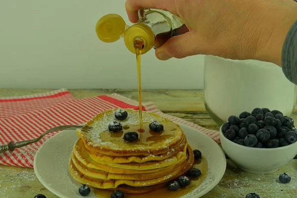 Nahaufnahme, wie man Ahornsirup auf einen Stapel Pfannkuchen gießt. Stapelweise Pfannkuchen mit frischen Blaubeeren und Ahornsirup — Stockfoto