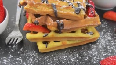 Meyveli Belçika waffle 'ları, erimiş çikolata ve siyah tabakta krema şekeri. Tatlı, tatlı waffle 'lar. Dönen arkaplan