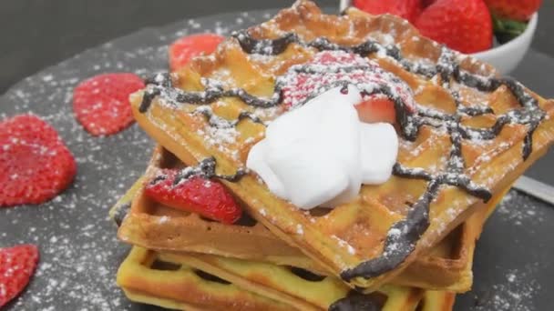 Belgische Waffeln zum Frühstück oder Brunch mit frischen Blaubeeren, Erdbeeren, geschmolzener Schokolade und Schlagsahne obendrauf. Rotierender Stapel Waffeln — Stockvideo