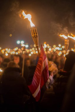 Letonya Lacplesa Günü fener alayı. Letonya bayrağıyla yanan meşaleler