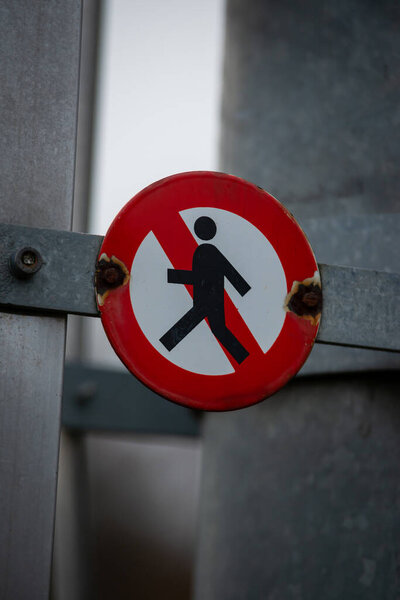 крупный план знака с красными людьми, ходящими с запрещенным символом на металлическом строении.