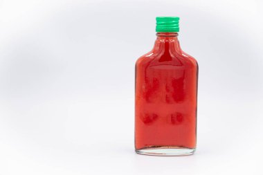 Kırmızı üzümlü bir şişe meyve suyu ve beyaz arka planda yeşil bir durdurucu.