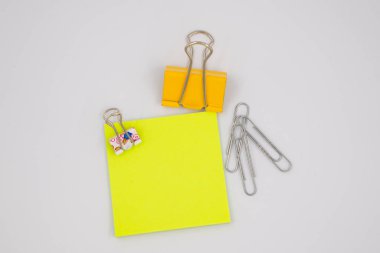 Metal ataçları beyaz üzerine izole edilmiş neon sarısı kağıt notalar.