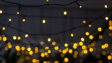 Bir çelengin bulanık ışıkları ve ön planda bir Noel ağacının dalları. Noel ve yeni yıl arkaplanı. Seçmeli odak, kopyalama alanı.