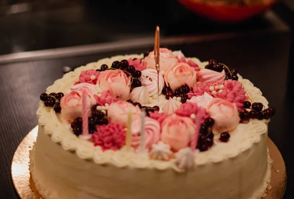 Birthday cake with pink whipped cream flowers and candles.