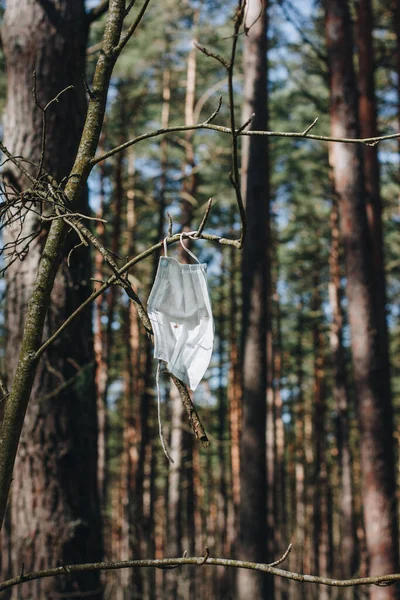 Ağaçta asılı kalan, rüzgarda sallanan, unutulan ya da rüzgarda savrulan tek kullanımlık cerrahi maskenin tek bir parçası.