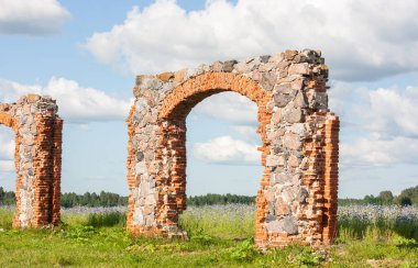 Eski, harap olmuş bir taş ve tuğla bina dramatik bulutlu bir gökyüzünün altındaki bir çayırda. Eski kırsal arazi.