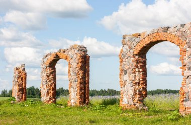 Eski, harap olmuş bir taş ve tuğla bina dramatik bulutlu bir gökyüzünün altındaki bir çayırda. Eski kırsal arazi.
