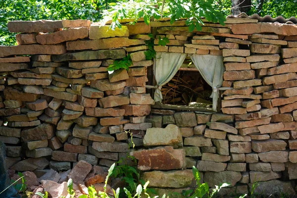 一堆石头就像一堵墙 它有一个有窗帘和木制框架的窗户 — 图库照片