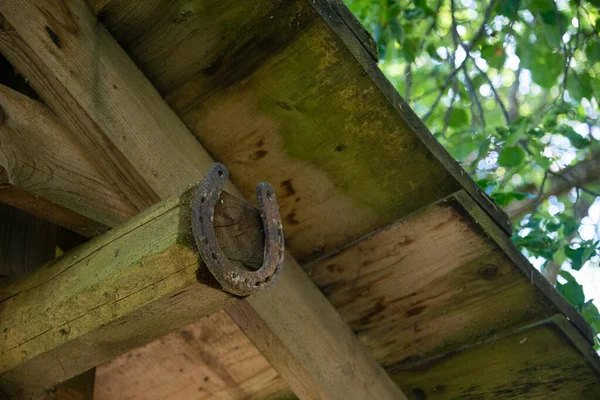 铁蹄钉在村舍的淡灰色木门上的旧的磨损的 生锈的金属马蹄马蹄是好运的标志 — 图库照片