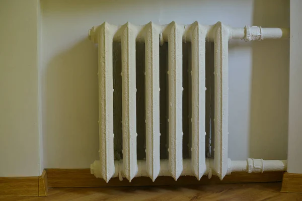 Pipes and a white heating radiator heat the room. heating season