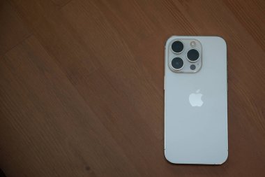 Riga Letonya - 25 Eylül 2022: Yeni çıkan iPhone 14 Pro 'nun kahverengi ahşap yüzeyde beyaz renkli arka görüntüsü.