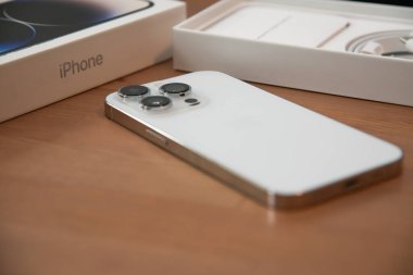 Riga, Letonya - 25 Eylül 2022: Yeni çıkan beyaz iPhone 14 Pro, ambalaj kutusu kahverengi ahşap arka planda.