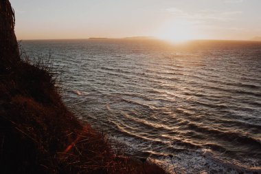 Yunanistan 'ın deniz kıyısındaki dalgalı suların güzel günbatımında dağlar uzaklarda.