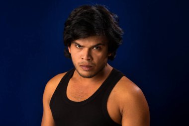 Portrait of a young man posing and showing his muscular body. The concept of a healthy lifestyle on blue background.