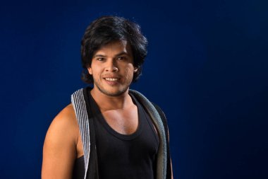 Portrait of a young man posing and showing his muscular body. The concept of a healthy lifestyle on blue background.