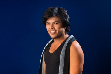 Portrait of a young man posing and showing his muscular body. The concept of a healthy lifestyle on blue background.