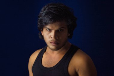 Portrait of a young man posing and showing his muscular body. The concept of a healthy lifestyle on blue background.