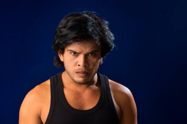 Portrait of a young man posing and showing his muscular body. The concept of a healthy lifestyle on blue background.