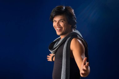 Portrait of a young man posing and showing his muscular body. The concept of a healthy lifestyle on blue background.
