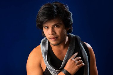 Portrait of a young man posing and showing his muscular body. The concept of a healthy lifestyle on blue background.