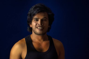 Portrait of a young man posing and showing his muscular body. The concept of a healthy lifestyle on blue background.