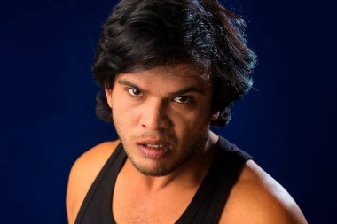 Portrait of a young man posing and showing his muscular body. The concept of a healthy lifestyle on blue background.