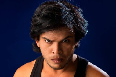 Portrait of a young man posing and showing his muscular body. The concept of a healthy lifestyle on blue background.