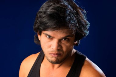 Portrait of a young man posing and showing his muscular body. The concept of a healthy lifestyle on blue background.