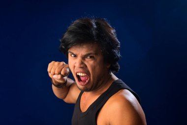 Portrait of a young man posing and showing his muscular body. The concept of a healthy lifestyle on blue background.