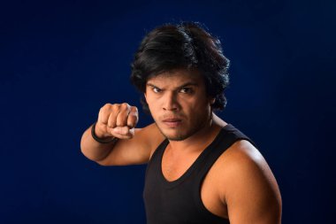 Portrait of a young man posing and showing his muscular body. The concept of a healthy lifestyle on blue background.