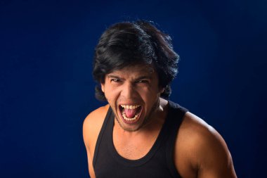 Portrait of a young man posing and showing his muscular body. The concept of a healthy lifestyle on blue background.