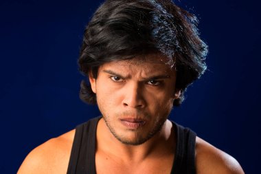 Portrait of a young man posing and showing his muscular body. The concept of a healthy lifestyle on blue background.
