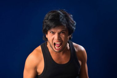 Portrait of a young man posing and showing his muscular body. The concept of a healthy lifestyle on blue background.