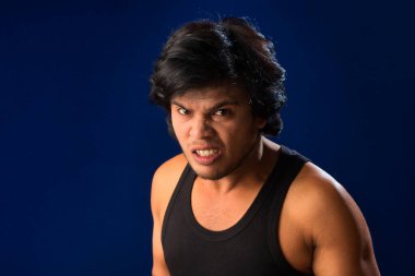 Portrait of a young man posing and showing his muscular body. The concept of a healthy lifestyle on blue background.