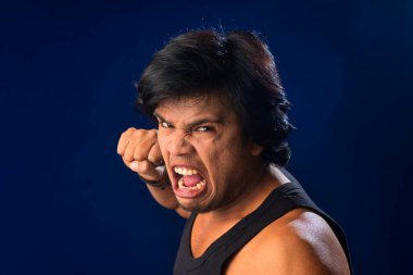 Portrait of a young man posing and showing his muscular body. The concept of a healthy lifestyle on blue background.