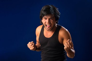 Portrait of a young man posing and showing his muscular body. The concept of a healthy lifestyle on blue background.