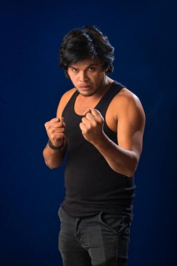 Portrait of a young man posing and showing his muscular body. The concept of a healthy lifestyle on blue background.